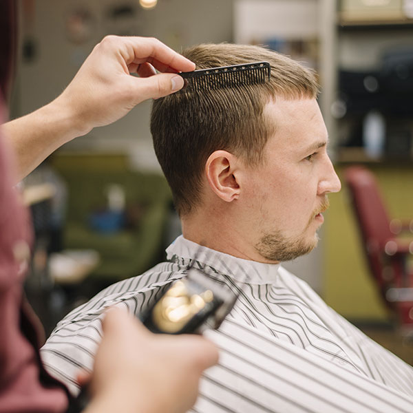 Corte de pelo con máquina y peine Barbero realizando corte de pelo con máquina y peine